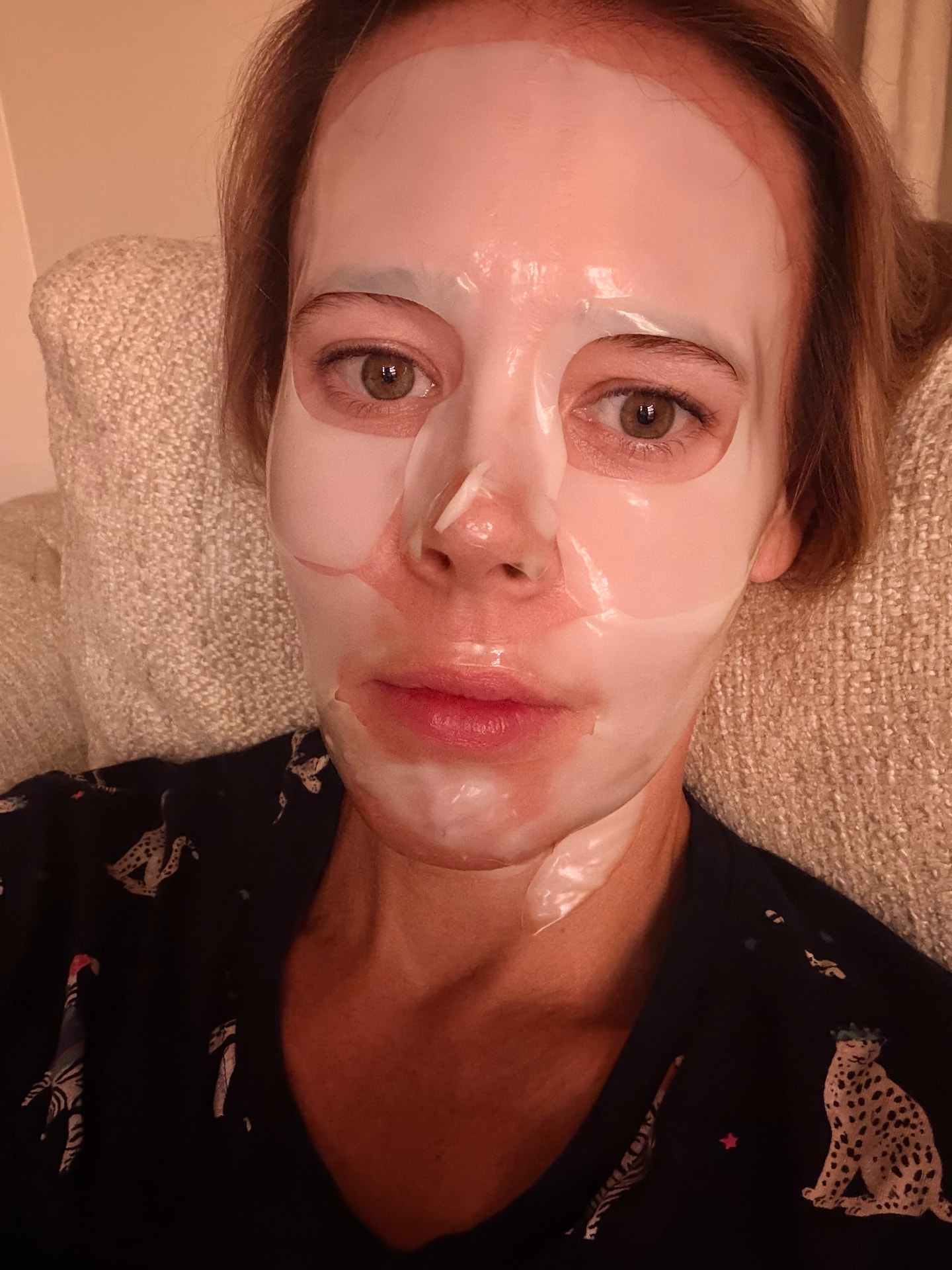 One of the podcast hosts reclining with a translucent sheet mask on her face